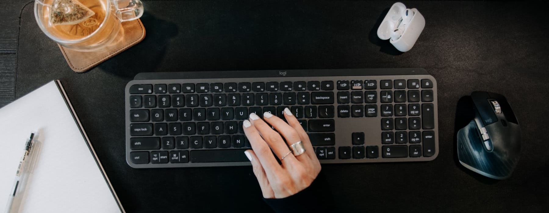 image of a hand on a keyboard beside an iced drink and common desk objects